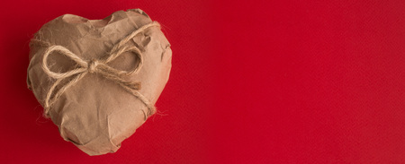 Heart in brown Wrapping Paper tied with rope bow on red background Valentine day surprise conceptの写真素材