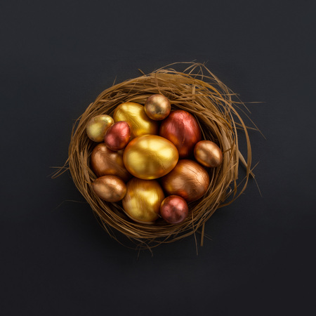 Happy Easter holiday greeting symbol stylish natural wooden grass nest with golden quail eggs on black backgroundの写真素材