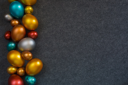Elegant fashion background with border frame of decorative color metallic Easter eggs on textile...