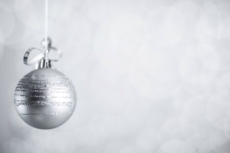 Silver Christmas new year ball with curly streamer ribbon bow over glittering bokeh lights...