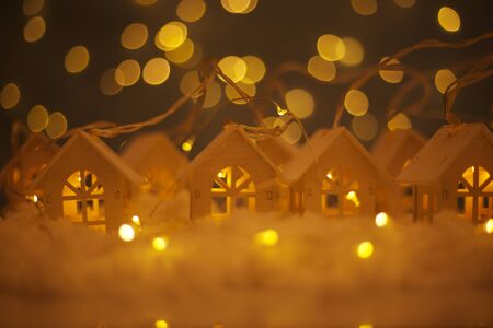 Christmas card of small glowing toy houses garland over bokeh lights background with copy space for...
