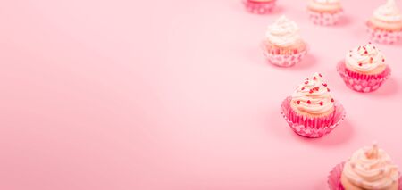 Valentine day love cupcakes decorated with cream and hearts on pink background with copy space for textの写真素材
