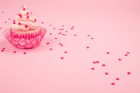 Valentine day love cupcake decorated with cream and hearts on pink background with copy space for textの写真素材
