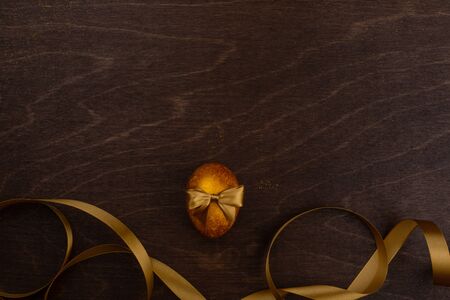 Golden luxury easter egg and ribbon composition on dark wooden background with copy space for text cardの写真素材