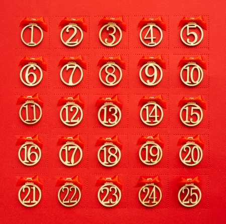 Abstract red Christmas advent calendar background with perforation windows in paper and day numbers and ribbon bowsの写真素材