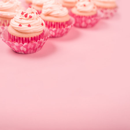 Valentine day love cupcakes decorated with cream and hearts on pink background with copy space for textの写真素材