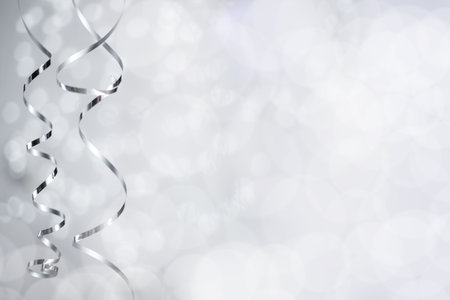 Silver Christmas new year curly streamer ribbon over glittering bokeh lights background with copy space for textの写真素材