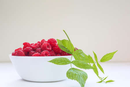 Big Pile of Fresh Raspberries and leaf in transparent bowl on the white backgroundの写真素材