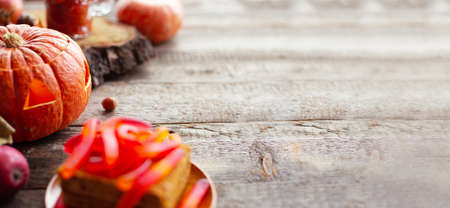 Halloween food still life abstract background with pumpkins, apples, cake, gummy worms, skull red drink and candlesの写真素材