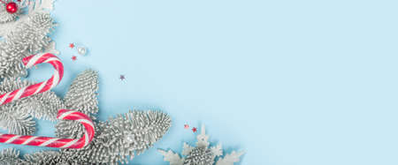 Frosted fir tree twigs and Christmas decorative candy canes on blue background with copy space for text template flat lay top view designの写真素材