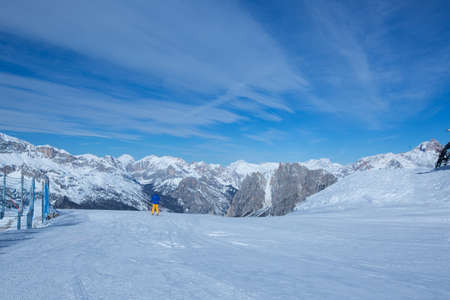 Male skier in blue and yellow clothes on slope with mountains in the background at Cortina d'Ampezzo Faloria skiing resort area Dolomiti Italyの写真素材