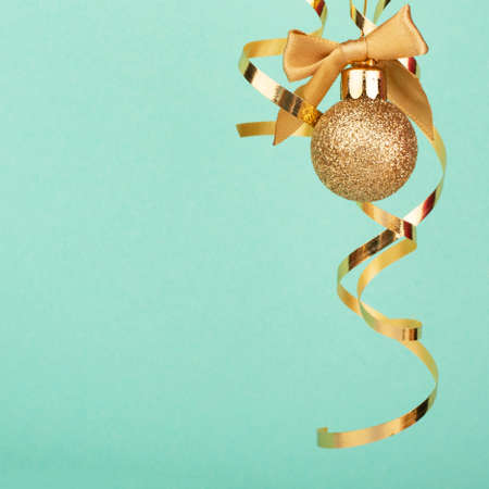 Christmas golden decoration ball bauble and curly ribbon with cow over light mint stylish background with copy space for text content minimal compositionの写真素材
