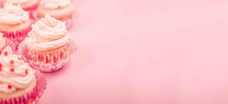 Valentine day love cupcakes decorated with cream and hearts on pink background with copy space for textの写真素材