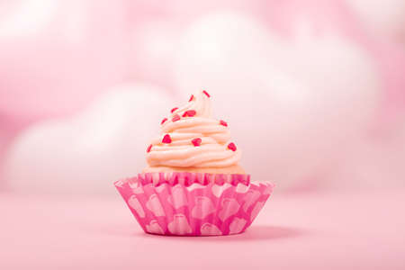 Valentine day love cupcake decorated with cream on pink and white party heart balloons background with copy space for textの写真素材