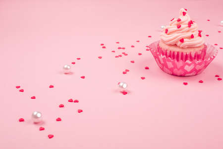 Valentine day love cupcake decorated with cream and hearts on pink background with copy space for textの写真素材