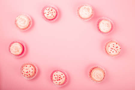 Valentine day love cupcakes decorated with cream and hearts on pink background border frame with copy space for textの写真素材
