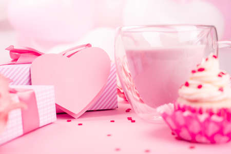 Valentine Day gift in a box wrapped in striped paper and tied with silk ribbon bow and dessert on pink balloons background with copy space for textの写真素材
