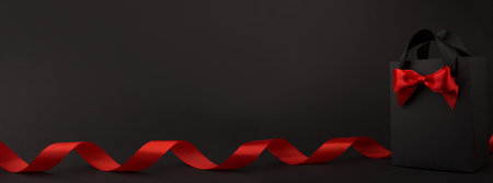 Gift in black paper bag with red ribbon on black background, design banner black friday sale concept copy space for textの写真素材