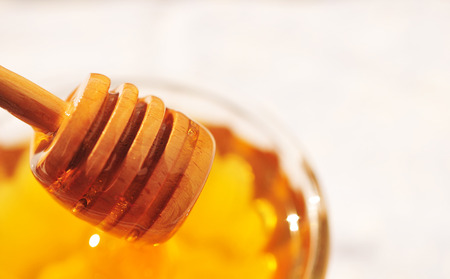 Honey macro with wooden honey dipper in the glass jar.の写真素材