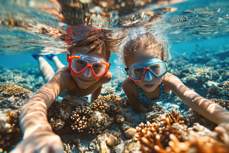 Cute little girl and her mother snorkeling underwater at tropical coral reefの素材