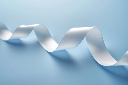 Curled white ribbon on blue background, close-up. Shallow DOFの素材