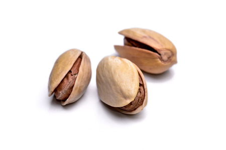 Three roasted pistachio nuts Pistacia vera isolated on white background