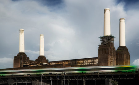 London, United Kingdom - October 01, 2006: Four chimneys of decommissioned coal Battersea power station with green tube train moving fast in foreground.のeditorial素材