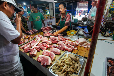 Khao Lak, Thailand - February 22, 2016:  Unknown man buying fresh pork meat from local merchant on market. Thai cuisine is renowned for its tasty food.のeditorial素材