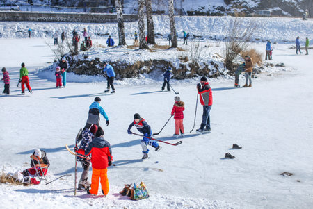 Liptovsky Hradok, Slovakia - March 03, 2018: People of all age groups enjoying sunny day, skating and playing ice hockey on a frozen lake, when temperatures drop on winter.のeditorial素材