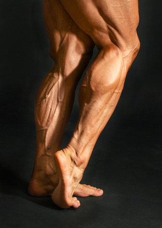 Detail of male bodybuilder back leg calf muscles on black background. Gastrocnemius and soleus.の写真素材