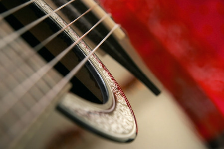 Detail on classical guitar six string, shallow depth of focus, with blurred red background.の写真素材