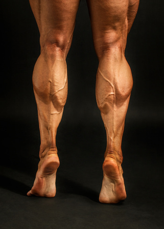 Detail on male bodybuilder calves muscles shot on black background.の写真素材
