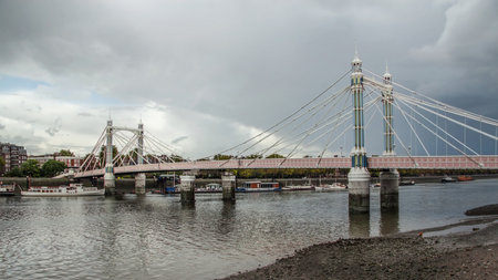 Albert Bridge over river Thames in London on gray overcast day. It connects Chelsea to Battersea and was opened in 1873のeditorial素材