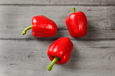 Tabletop view - three red bell peppers on rustic gray wood desk.の写真素材
