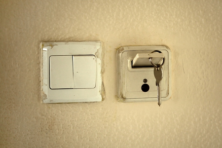 Classic mechanic key with card in slot to activate electricity in hotel room. Old dirty wall and...