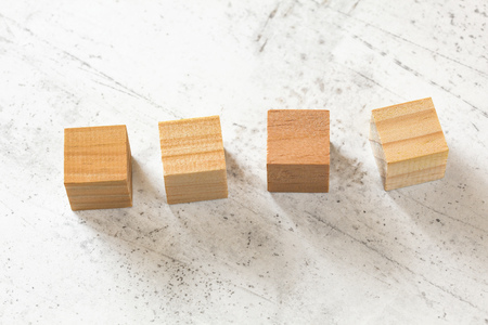 Four blank wooden cubes on white cement board