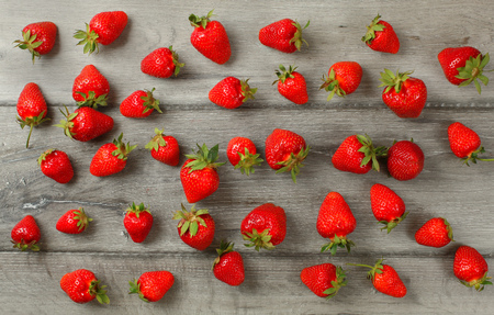 Tabletop view - ripe strawberries, freshly picked spilled on gray wood boards deskの写真素材