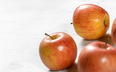 Bright red and yellow apples - fuji kiku variety - on white board, sapce for text left.