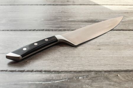 Chef's knife on wooden boards desk.