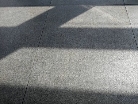 Shadows from morning sun on concrete airport waiting hall floor. Abstract natural light vs...