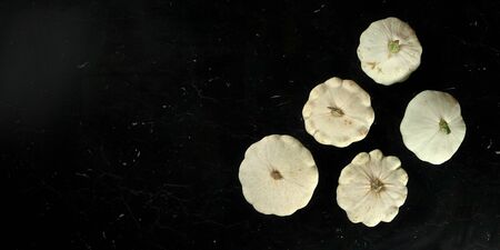 Five white pattypan squash on black marble like board, view from above, wide banner with space for text left sideの写真素材