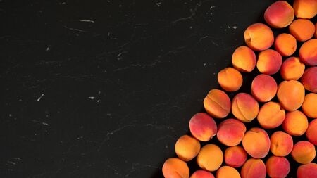 Apricots on one side of board, creating diagonal line dividing wide banner with space for text left sideの写真素材