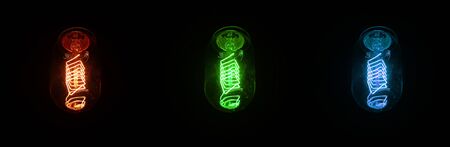 Retro looking light bulb glowing on dark background, bright wire visible in glass - colour can be changed with hue saturation tool.の写真素材