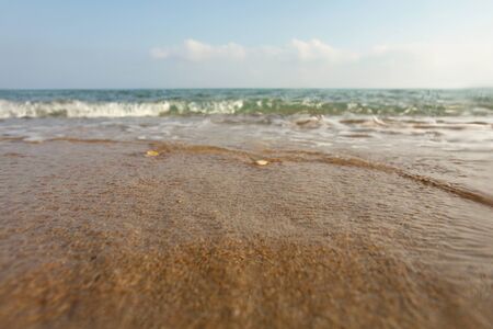 Wet sand on the beach, sea in distance, low angle photo on ground level, lens covered with some...