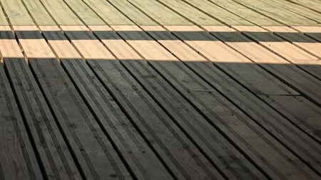 Regular exterior wooden board floor, sun casting shadow from side.の写真素材