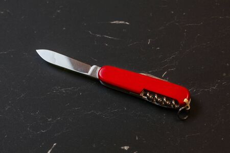 Red pocket knife on black table.の写真素材