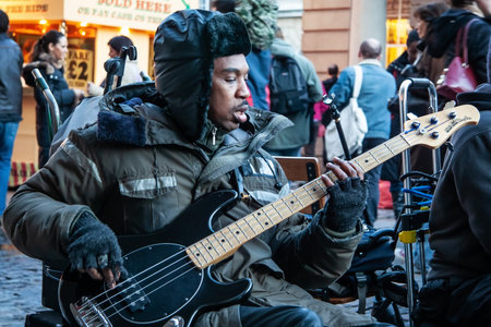 London, United Kingdom - November 25th, 2006: Unknown busker plays bass guitar and signs at Covent Garden. Street performers are performing often in this area, as it's popular tourist spot.のeditorial素材