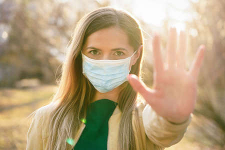 Young woman wearing disposable single use blue virus face mouth nose mask, closeup portrait, banner with space for text right side. Coronavirus covid-19 outbreak prevention conceptの写真素材