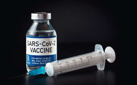 Coronavirus Covid 19 vaccine concept (own design, not real product) - small glass bottle with silver cap, syringe near, closeup detail on black backgroundの写真素材