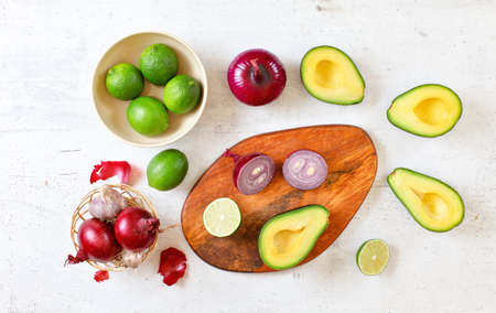 Avocado halves, limes and onions - basic guacamole ingredients on white working board, flat lay photoの写真素材